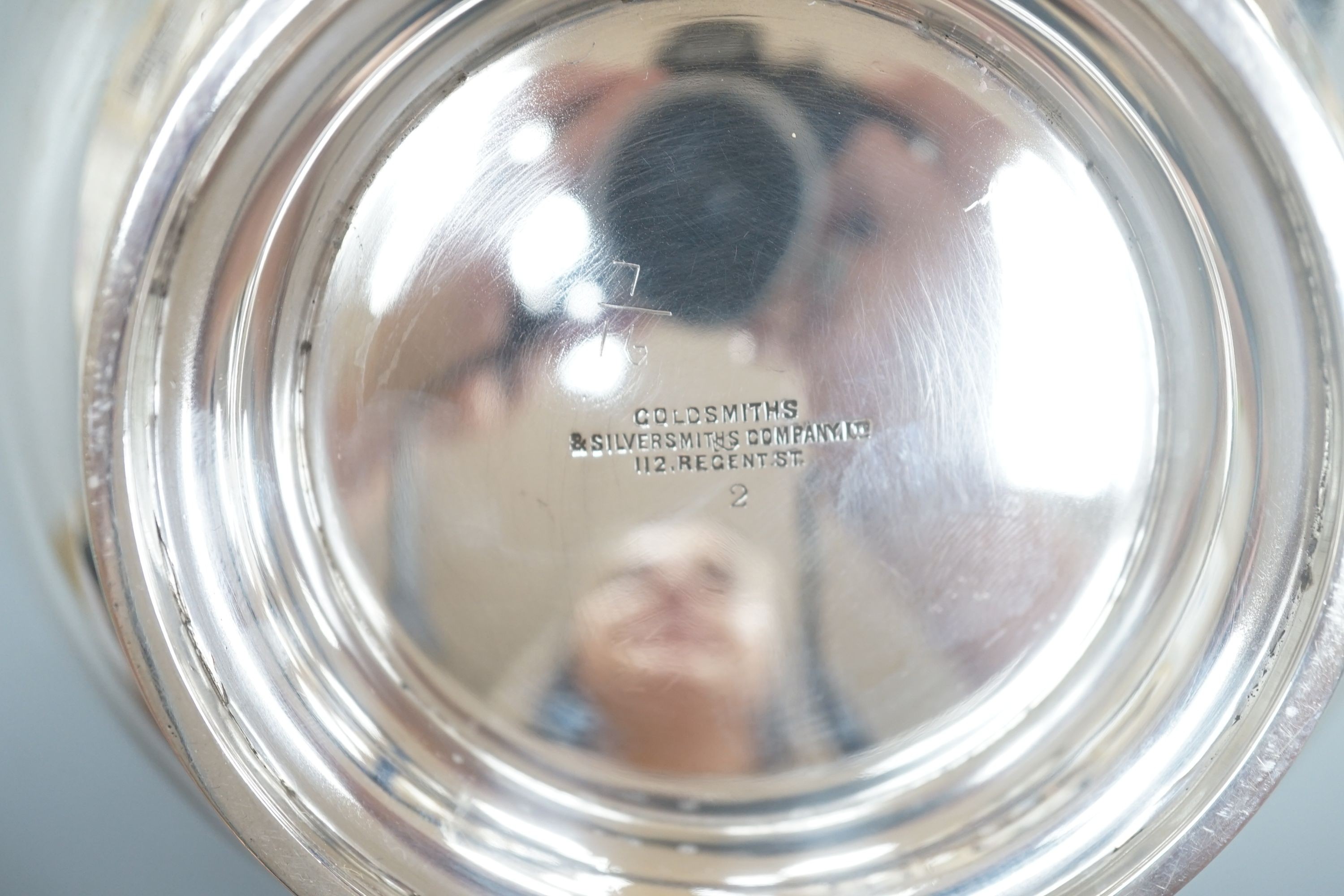 An Edwardian silver circular bowl, with three piece harp shape handles, Goldsmiths & Silversmiths Co Ltd, London 1906, on pedestal foot, diameter 16.25cm, 14oz.